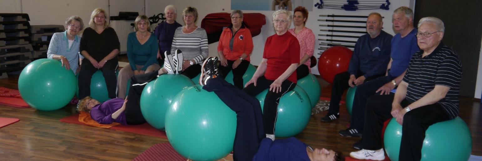 Gruppe von Menschen bei einer Bewegungstherapie mit großen grünen Gymnastikbällen.