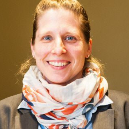 Nahaufnahme einer lächelnden Frau mit blondem Haar und einem farbenfrohen Schal.